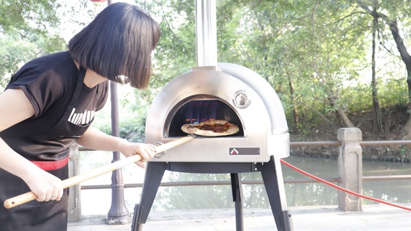 Persona cocinando pizza en el horno portátil